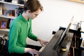 Dan Paradis plays piano in a practice space 