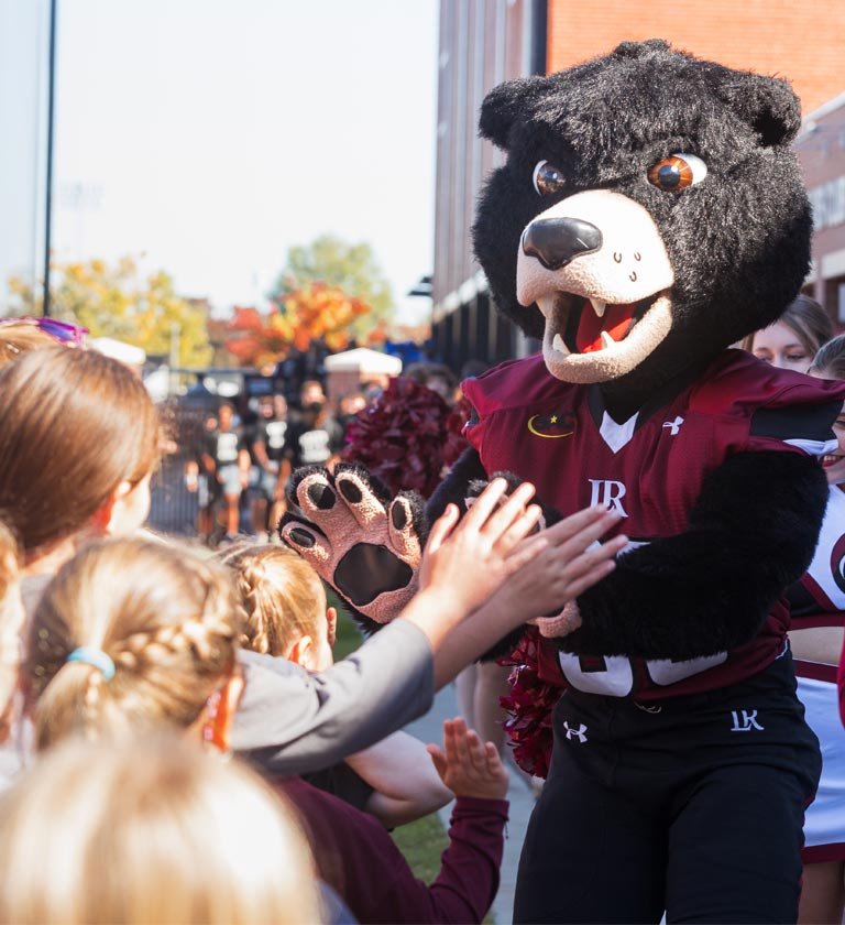 Joe Bear mascot greets kids before entering football field on game day