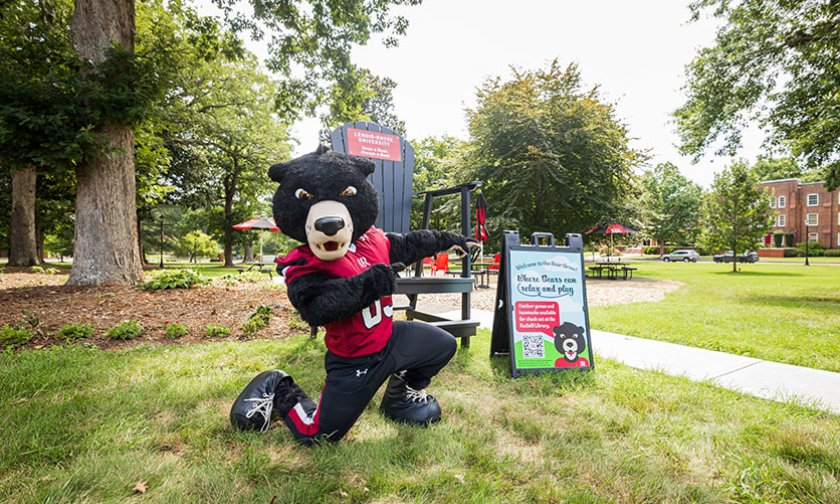 Joe Bear poses in front of the Bear Grove Big Chair and a welcome sign