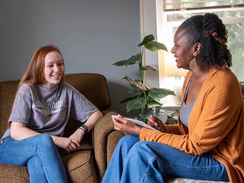 A counselor talks with a student on a couch in her office