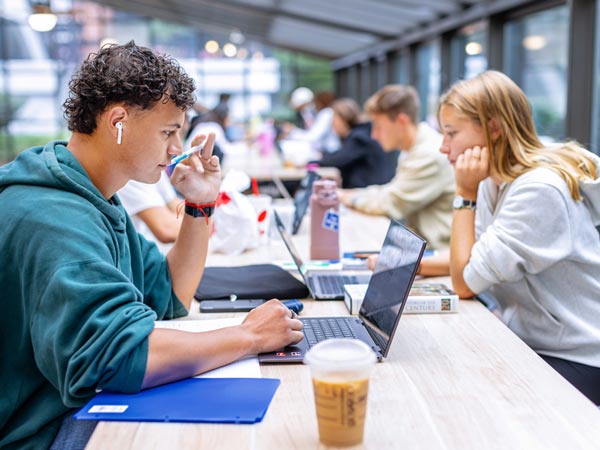 Students working at table on laptops on a coffee shop