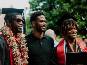 Two graduates from the Class of 2022 pose for photos outside after commencement ceremony