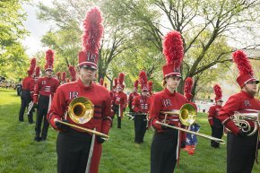 The Spirit of LR marching trombone section lines up under trees