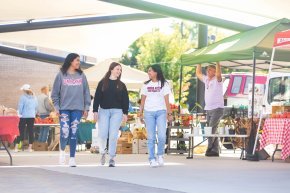 Students walk through a downtown farmers market