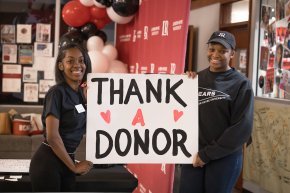 Two female students hold a poster with thank a donor written on it