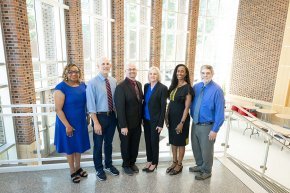 Six members of the grant writing team for the Noyce scholarship program stand in the George Hall lobby