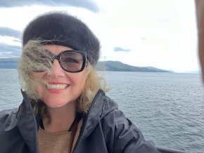 Laura Hope Gill on a boat with Scottish coastline in the background