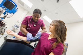 Two nursing students practice with a blood pressure cuff