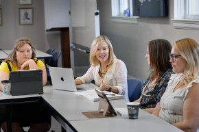 Susan McArver collaborates with students around a conference table