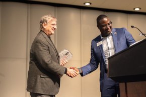 Fred Whitt and Harry Titus shake hands by the podium on the PE Monroe stage