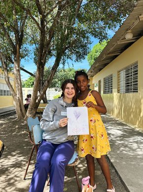 Alyssa Bailey with a young girl showing her drawing outside a clinic