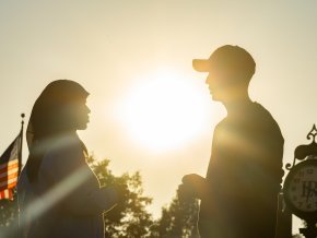 Silhouette of two students facing each other outside during sunset