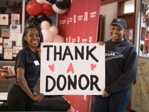 Two female students hold a poster with thank a donor written on it