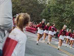 Spirit team marches in the 2023 homecoming parade with band visible behind them