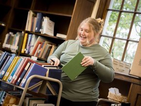 Lillian Cummines files books on a cart in Rudisill Library