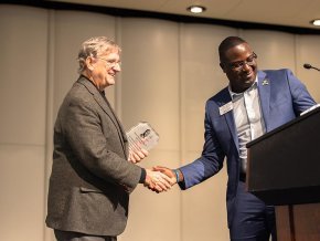 Fred Whitt and Harry Titus shake hands by the podium on the PE Monroe stage