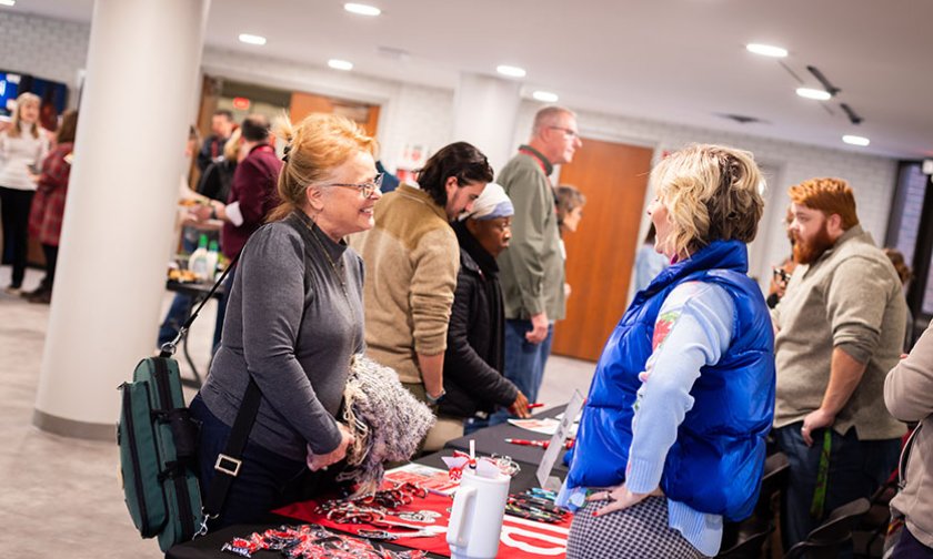 An LTSS student chats with a staff member over a table at a student services fair