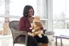 Amber Currie sits inside while holding a orange and white cat