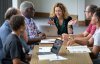 Professor talks with students around table in classroom